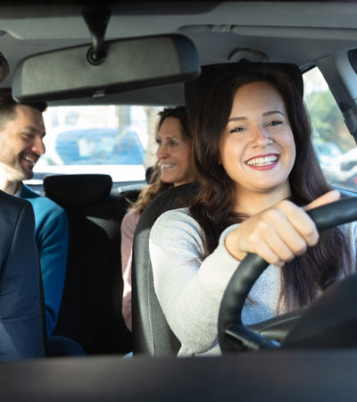 A group of smiling, young businessmen and women sharing a 4-seater car ride