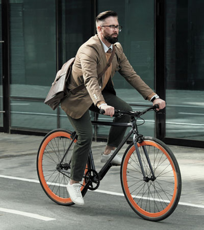 Mature businessman riding to his work by bike along the streets in the city