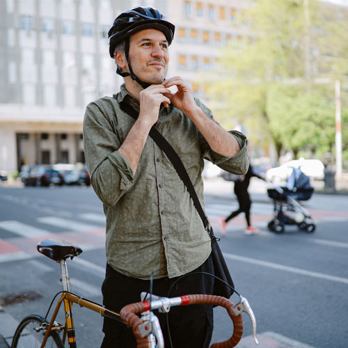 Business man in green shirt putting helmet on ready to cycle through city