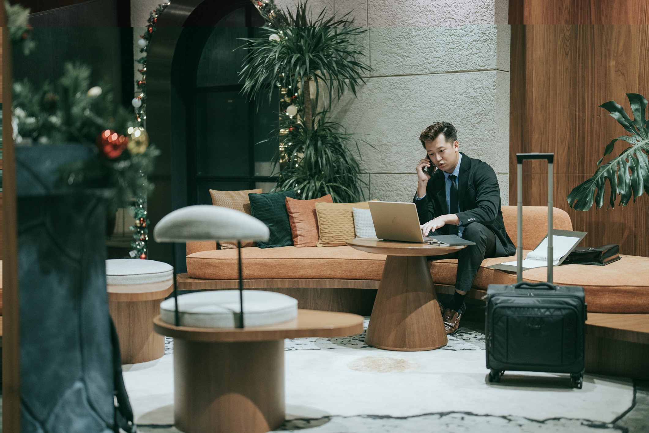 Asian businessman talking over phone at airport lounge sitting on sofa