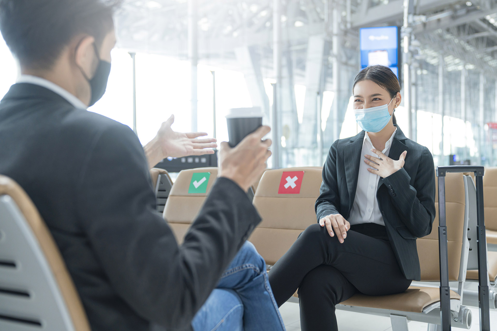 businessman and woman with face mask protection casual meeting with social distancing seat at airport terminal new lifestyle business concept business colleagues talking in the airport departure lounge