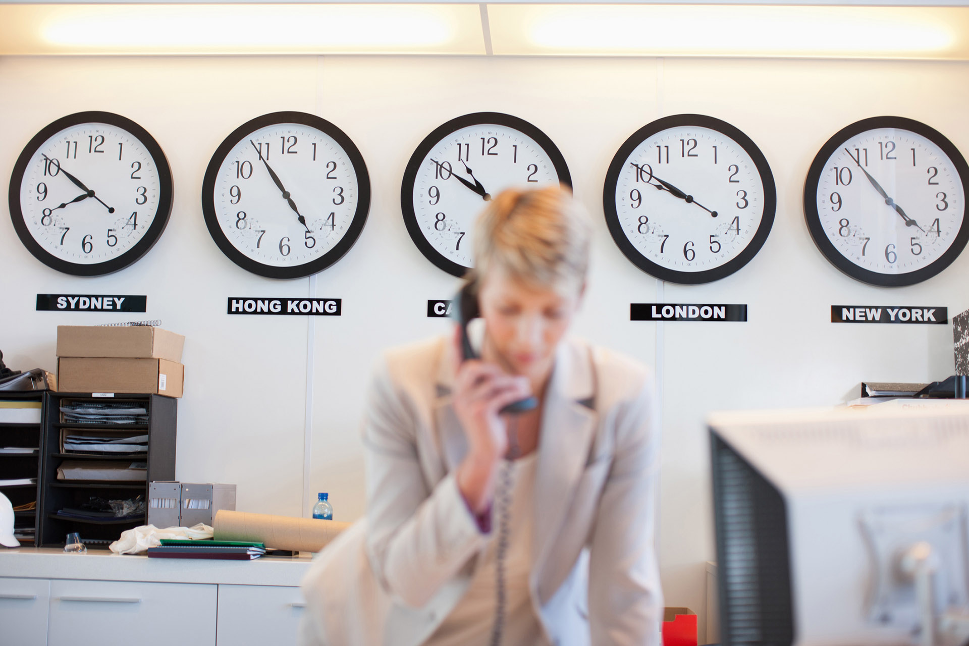 Businesswoman talking on phone in office working across time zones