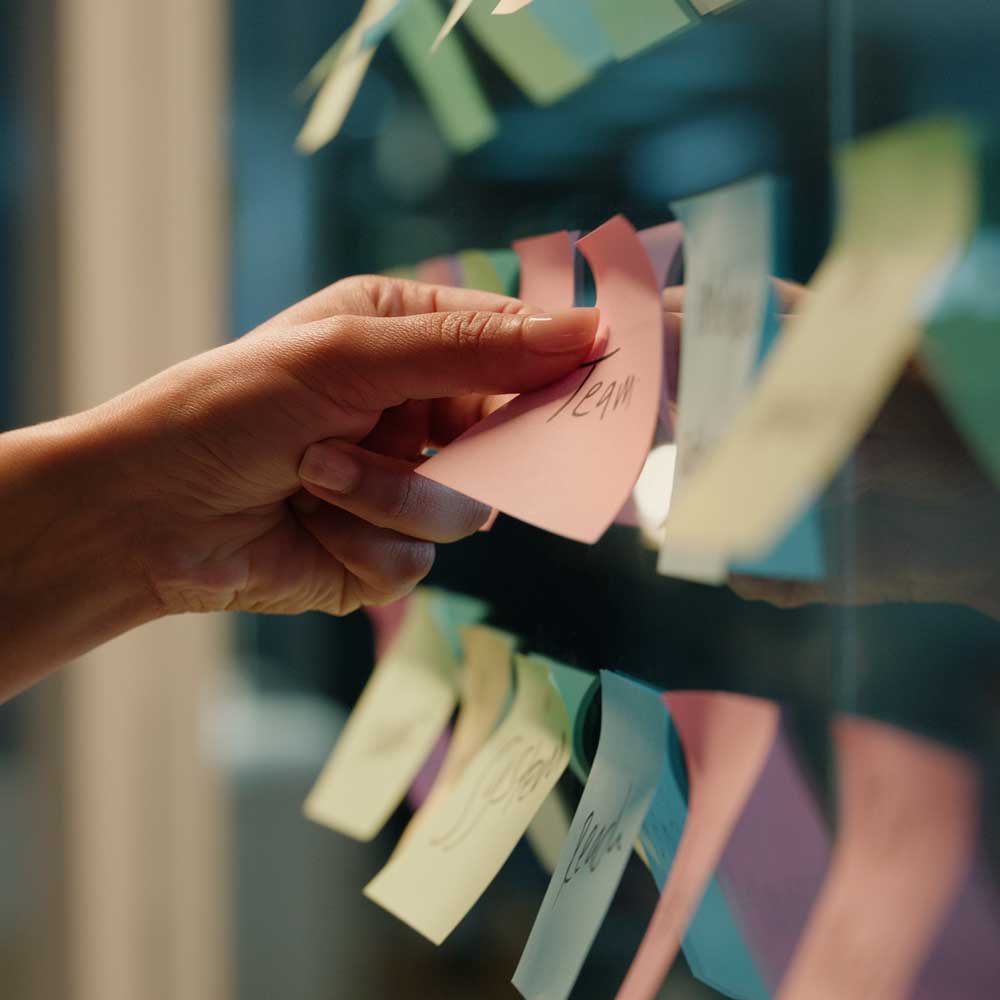 A board of sticky notes on a glass wall