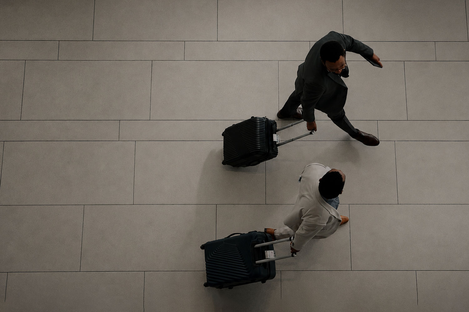 Business travellers walking across airport with wheelie cases